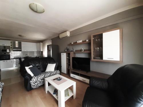 ein Wohnzimmer mit einem schwarzen Sofa und einem Tisch in der Unterkunft Apartment Gloria in Zadar