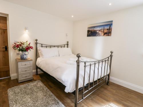 - une chambre avec un lit et un vase de fleurs dans l'établissement Stag Cottage at Broadings Farm, à Whitby