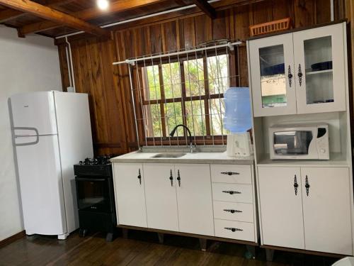 a kitchen with white cabinets and a white refrigerator at Cabanas da Vó Nena in Palhoça