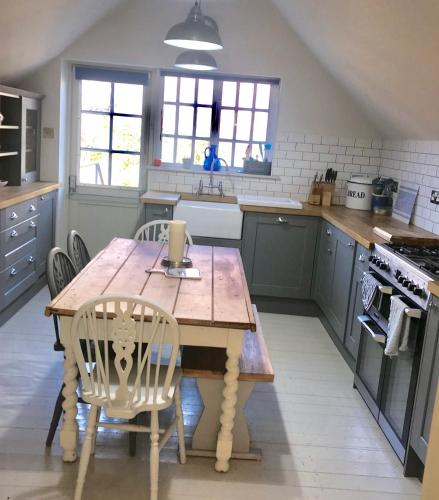 a kitchen with a wooden table and chairs at Duke of Monmouth penthouse luxury apartment Lyme Regis 3 bedroom parking Hot tub Garden dog friendly in Lyme Regis