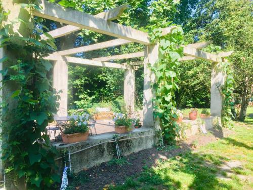 uma pérgola de madeira com vasos de plantas em Propriété Les Ruisseaux em Seine-Port