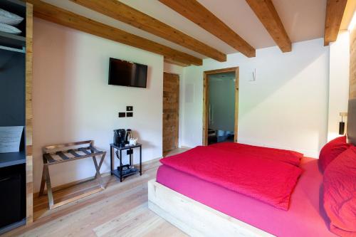 a bedroom with a red bed and a flat screen tv at B&B fiordimelo in Cavalese