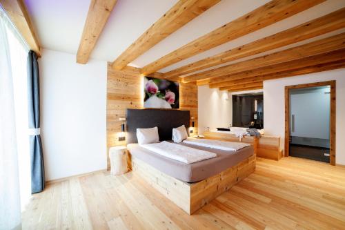 um quarto com uma cama num quarto com pisos em madeira em B&B fiordimelo em Cavalese