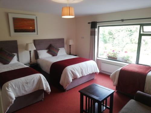 a hotel room with two beds and a window at O'Sheas Ceol Na Habhann B&B in Kenmare
