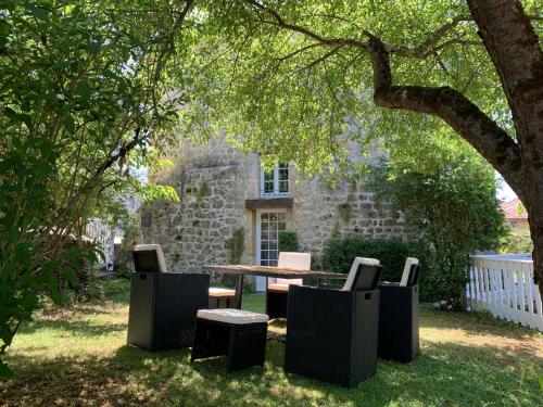 a table and chairs under a tree in a yard at Gite du moulin in Pranzac