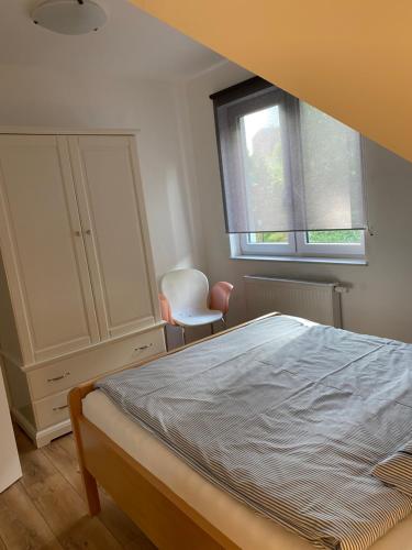 a bedroom with a bed and a window and a chair at Lesny Apartament in Ostrzyce