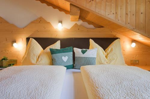 two beds in a room with wooden walls and ceilings at Appartamenti Pastüres in Colfosco
