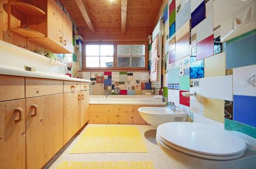 a bathroom with a toilet and a sink and a tub at Appartamenti Pastüres in Colfosco