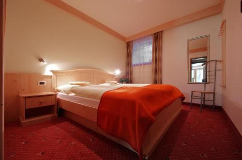 a bedroom with a bed with an orange blanket on it at Appartamenti Pastüres in Colfosco