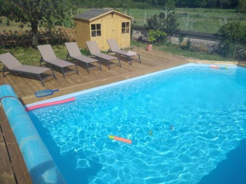 - une piscine avec des chaises et une cabane pour chiens dans l'établissement COTTAGE SAINTE GENEVIEVE, à Champigny-sur-Veude