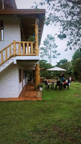 a house with a deck and a table and umbrella at CABAÑA LOS NOGALES in San Agustín