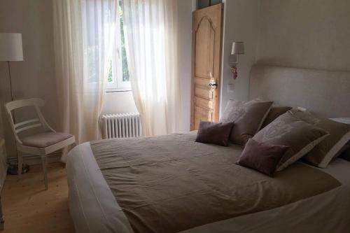 um quarto com uma cama grande com uma cadeira e uma janela em La Maison du Rempart em Eguisheim