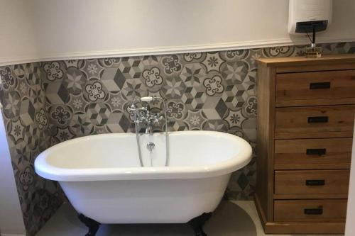 a bathroom with a white bath tub next to a dresser at La Maison du Rempart in Eguisheim