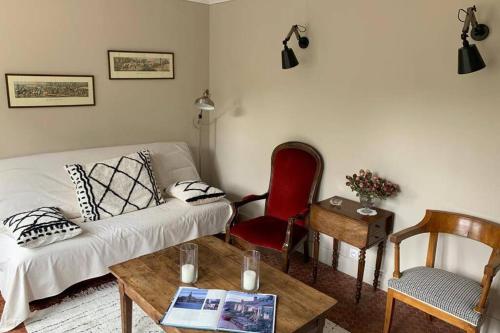un salon avec un canapé blanc et une chaise rouge dans l'établissement LA PETITE MAISON de Chenillé Changé, à Chenillé-Changé