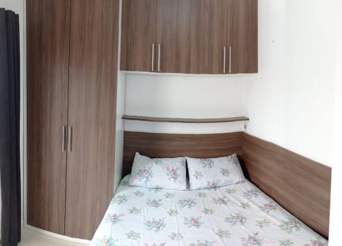 a bedroom with a bed and wooden cabinets at Temporada de frente para o mar in Caraguatatuba