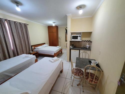 a hotel room with two beds and a table and chairs at JF Flat - Hotel in Ribeirão Preto