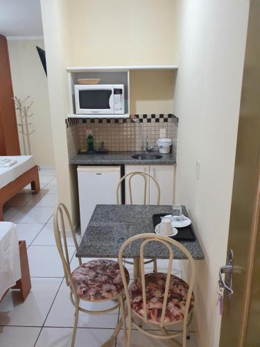 a kitchen with a table and chairs and a microwave at JF Flat - Hotel in Ribeirão Preto
