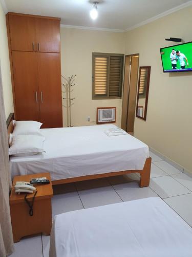 a hotel room with two beds and a tv at JF Flat - Hotel in Ribeirão Preto