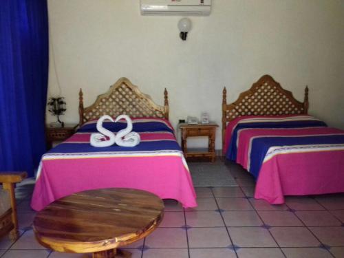 a bedroom with two beds and a wooden table at Hotel Colonial Rivera in Iguala de la Independencia