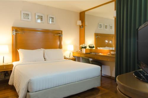 a hotel room with a bed and a mirror at AT EASE saladaeng by AETAS in Bangkok