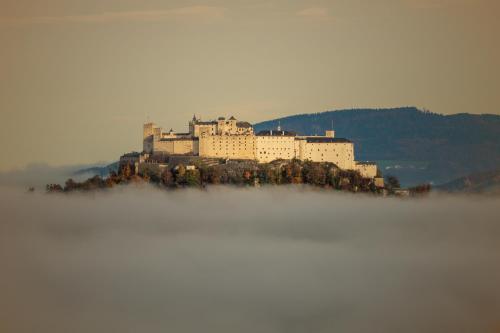 a castle sits on an island in the middle of the fog at Alpenhaus Donnerkogel in Annaberg im Lammertal
