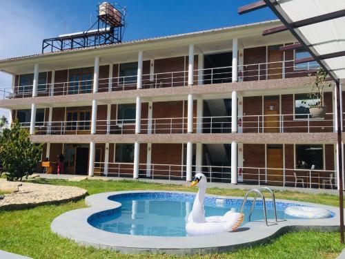 un edificio con una piscina y un cisne frente a ella en Runaway Eco Hotel, en Carhuaz