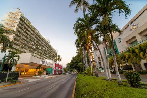 an empty city street with palm trees and buildings at Emporio Acapulco in Acapulco
