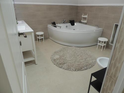 a bathroom with a tub and a sink and a rug at Blue Sky House in Baloteşti