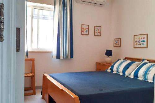 Schlafzimmer mit einem Bett mit blauer Bettwäsche und einem Fenster in der Unterkunft Cozy beach front apartment in Portimão