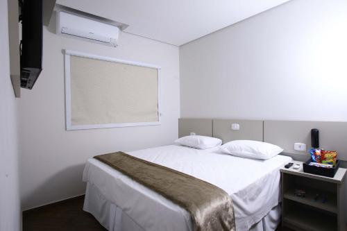 a white bedroom with a bed and a window at Hotel Pro Tork Confort in Santo Antônio da Platina