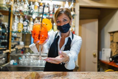 une femme portant un masque facial tenant un verre dans l'établissement Hotel Ristorante Garibaldi, à Frosinone