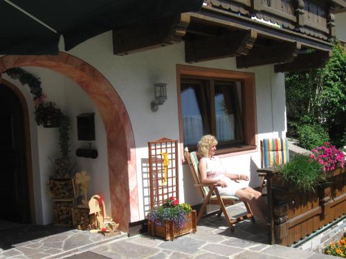 a woman sitting in a chair on the porch of a house at Appartements-Klaus in Neustift im Stubaital