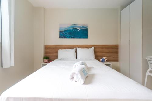 ein Schlafzimmer mit einem weißen Bett und einem Handtuch darauf in der Unterkunft Aloha Residence in Porto De Galinhas