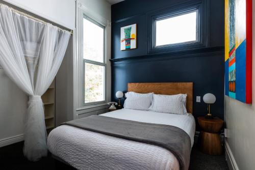 a bedroom with a bed with blue walls and two windows at The Metro Hotel in San Francisco