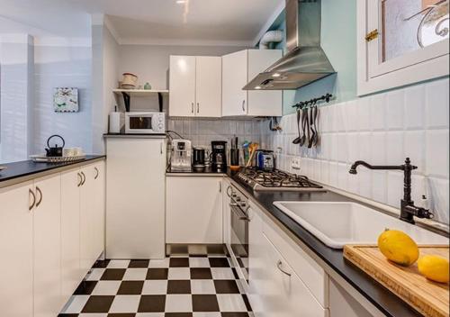 a kitchen with white cabinets and a checkered floor at Beach Apartment Montemar No.1 - perfect ocean view in Sóller