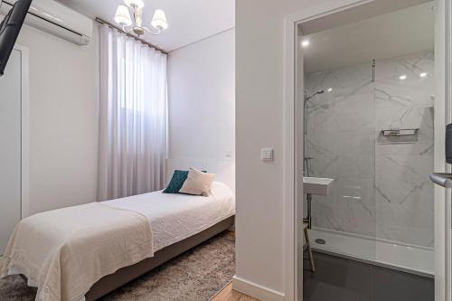 Schlafzimmer mit einem Bett und einer Glasdusche in der Unterkunft Templo Boutique Hotel in Évora