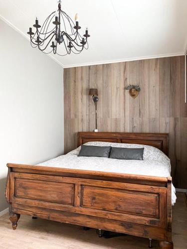 a bedroom with a large wooden bed with a chandelier at 4seasonshouse in Losser