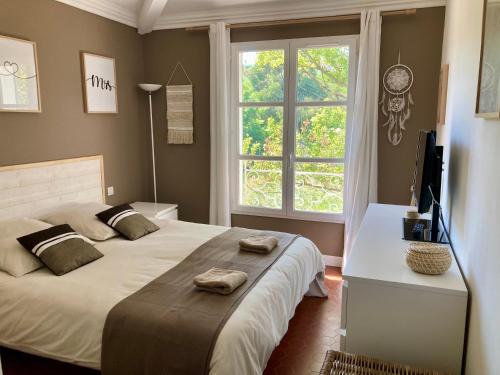 Schlafzimmer mit einem Bett, einem TV und einem Fenster in der Unterkunft Les Restanques Maison du lac 4 chambres in Grimaud