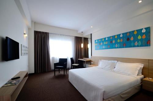 a hotel room with a white bed and a desk at StarCity Hotel in Alor Setar