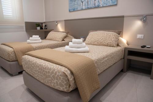 - 2 lits dans une chambre avec des serviettes dans l'établissement Virgilio hosting Casa Nuovissima Vista Mare, à Torre Pali