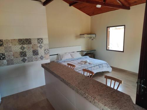 a bedroom with a bed and a table and chairs at Chalé caminho das cachoeiras in São Thomé das Letras