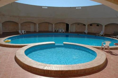 a large pool in a building with chairs around it at شاليه بقرية أندلسيه بمطروح يرى البحر in Marsa Matruh