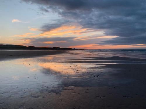 a sunset on a beach with a cloudy sky at Brada View Bamburgh in Bamburgh