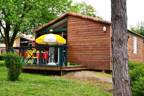 a small house with an umbrella and a playground at VVF Vienne Poitou in La Bussière