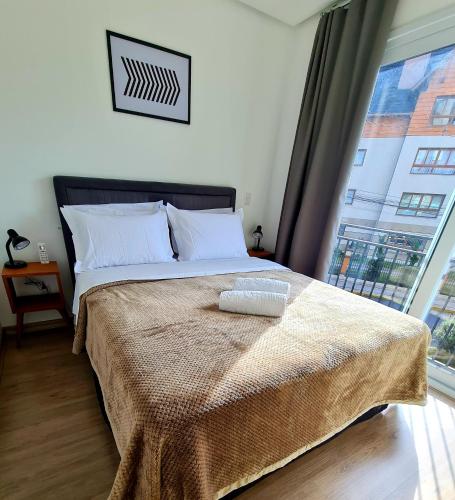 a bedroom with a bed with a large window at Loft Gramado in Gramado