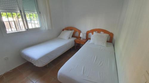 Apartment in Rota Cadiz, Air Cond, Wifi, Patio في روتا: سريرين في غرفة صغيرة بها نافذتين