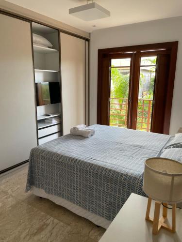 a bedroom with a bed and a sliding glass door at Casa Praia do Forte - Piscinas naturais in Farol