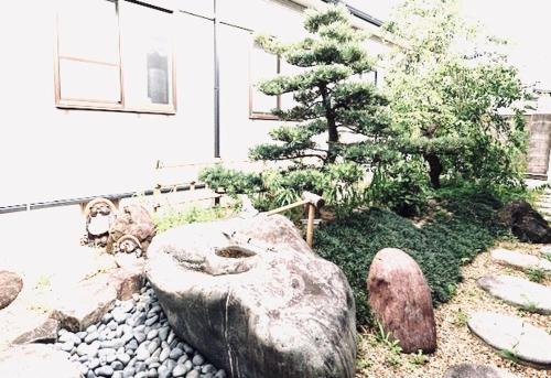 a garden with a tree and rocks and a building at Hotel Sunmarine in Tarui