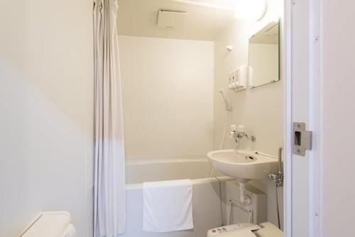 a white bathroom with a sink and a toilet at Hotel Sunmarine in Tarui