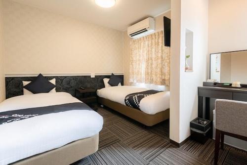 Hotel Sunmarine في Tarui: غرفة فندقية بسريرين ومكتب